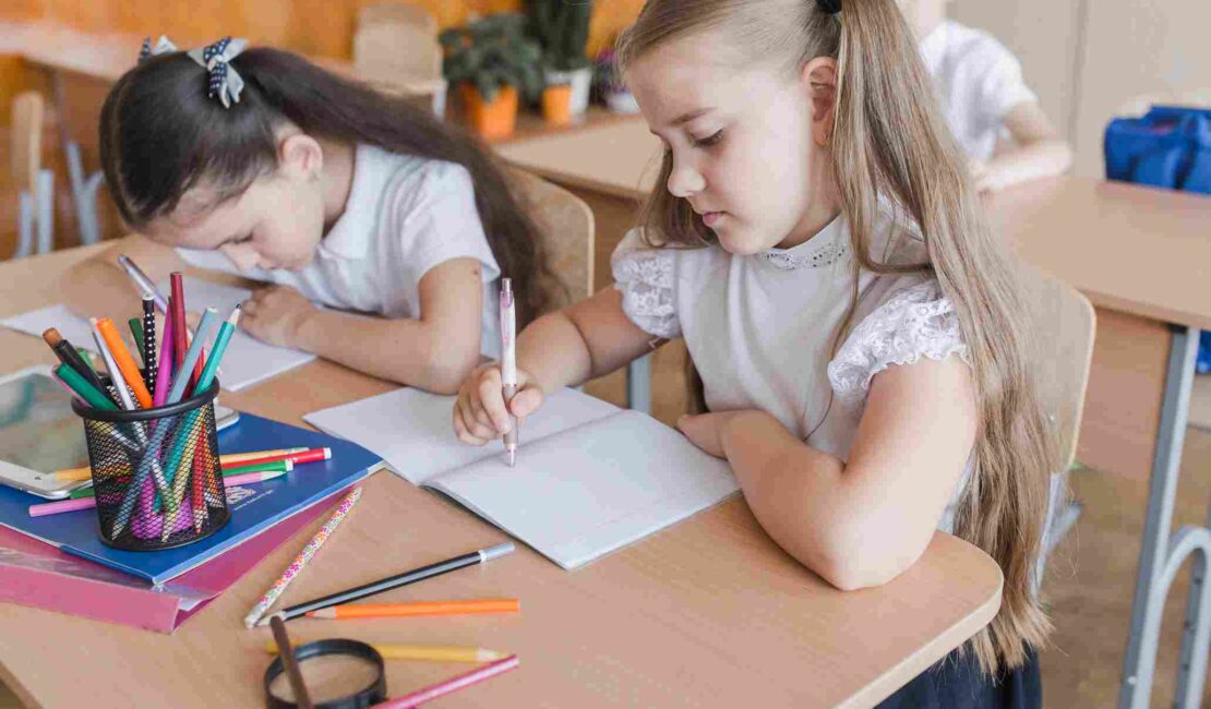 Girls fulfilling exercise in notebook