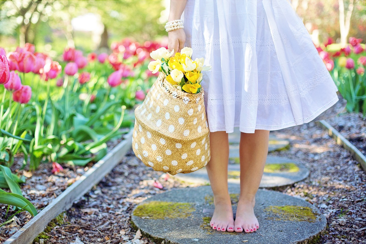 Girl carrying a flower basket, walking thorough a walkway with plant growth on each side. Blog Poster for "6 Creative Small Garden Ideas: Plantation & Design Guide"